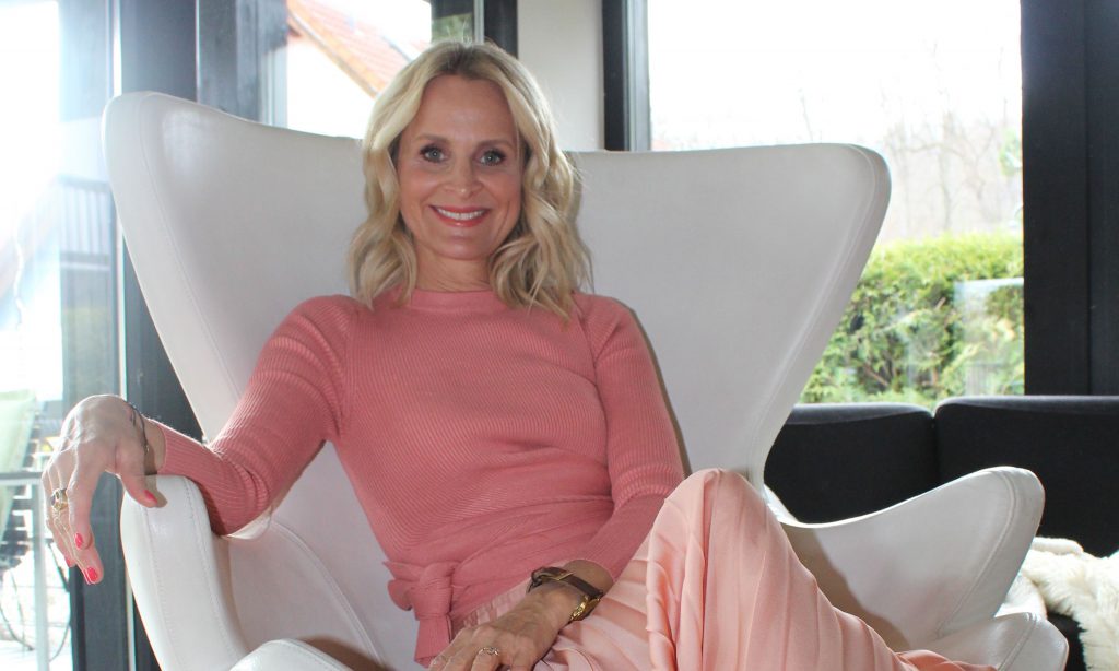 Nina Wirtz macht es sich mit ihrem rosa/pinken Look auf dem Sofa bequem
